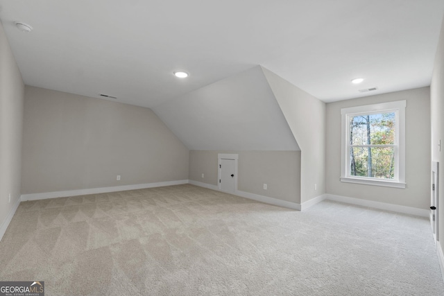 bonus room featuring vaulted ceiling and light colored carpet