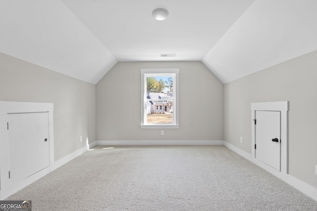 bonus room with vaulted ceiling and light carpet