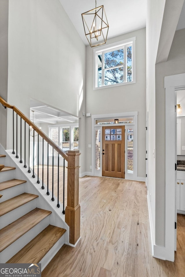 entrance foyer with a towering ceiling, an inviting chandelier, and light hardwood / wood-style flooring