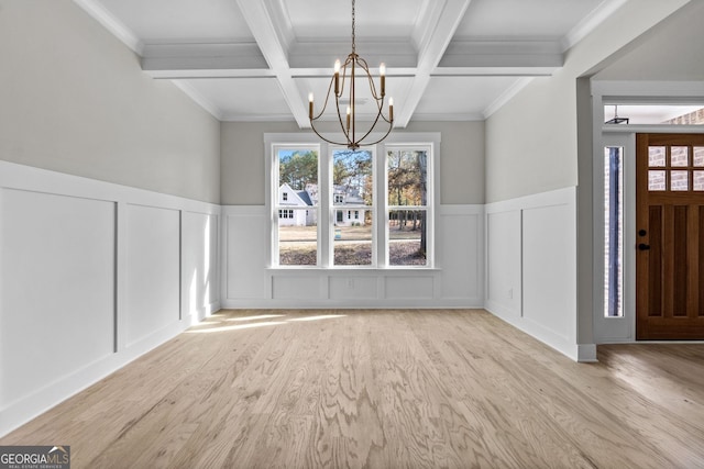 unfurnished dining area with coffered ceiling, beamed ceiling, light hardwood / wood-style floors, ornamental molding, and a chandelier