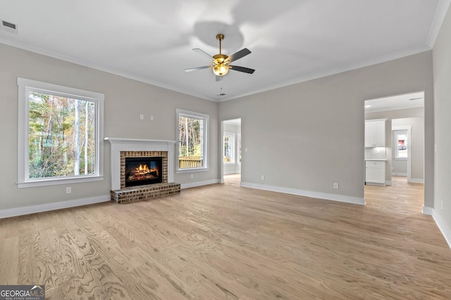 unfurnished living room featuring ceiling fan, ornamental molding, a fireplace, and light hardwood / wood-style floors