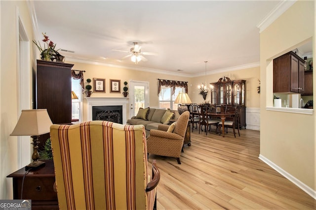 living room with ornamental molding, ceiling fan, and light hardwood / wood-style floors