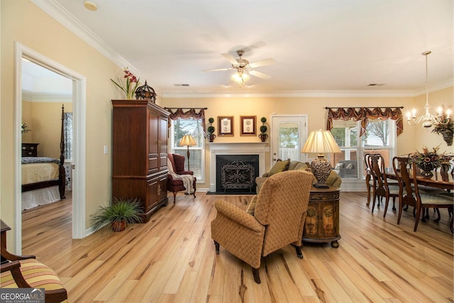 living room featuring crown molding, ceiling fan with notable chandelier, and light hardwood / wood-style flooring