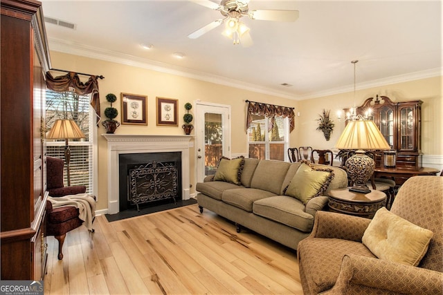 living room featuring crown molding, plenty of natural light, and light hardwood / wood-style flooring