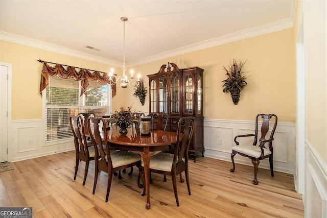 dining area featuring ornamental molding, light wood-type flooring, and a notable chandelier