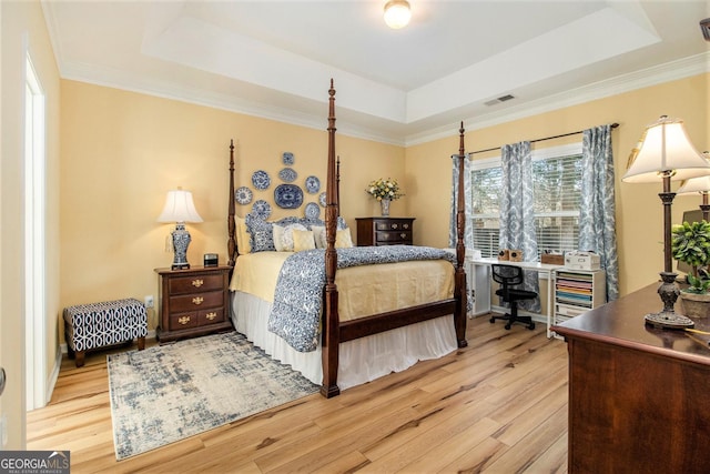 bedroom featuring a raised ceiling, ornamental molding, and light hardwood / wood-style floors