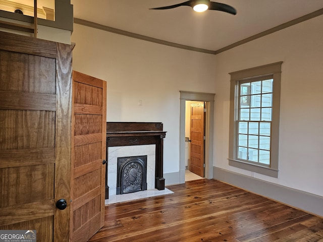 unfurnished living room featuring a tile fireplace, ornamental molding, dark wood-type flooring, and ceiling fan