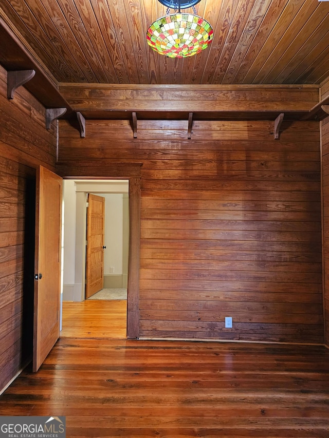 empty room with wood-type flooring, wooden ceiling, and wooden walls