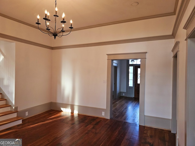 empty room featuring dark wood-type flooring, ornamental molding, and an inviting chandelier