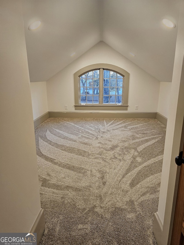 additional living space featuring lofted ceiling and carpet flooring