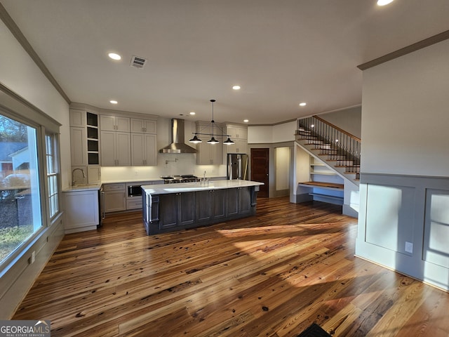 kitchen with wall chimney exhaust hood, a center island, ornamental molding, stainless steel fridge, and pendant lighting