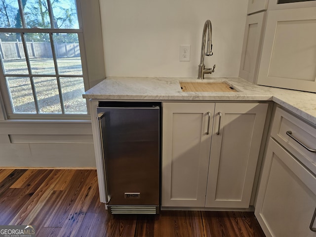 kitchen with refrigerator, white cabinetry, sink, dark hardwood / wood-style flooring, and light stone countertops