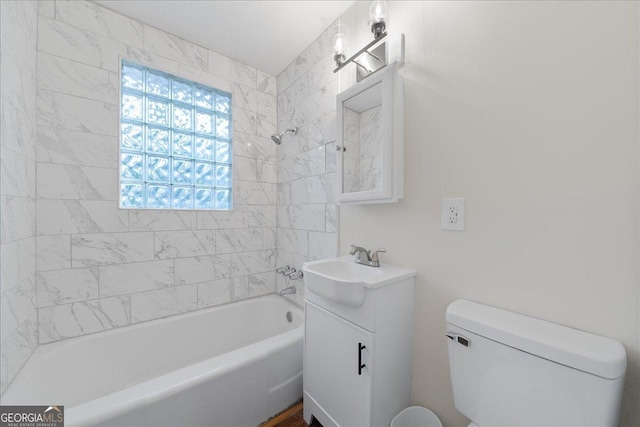 full bathroom featuring vanity, tiled shower / bath, and toilet