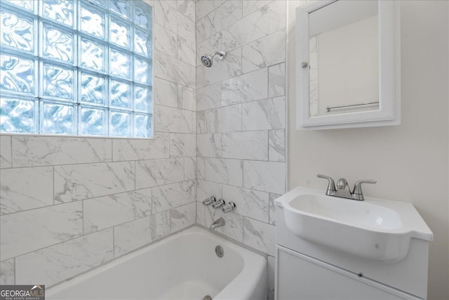 bathroom featuring tiled shower / bath combo and vanity