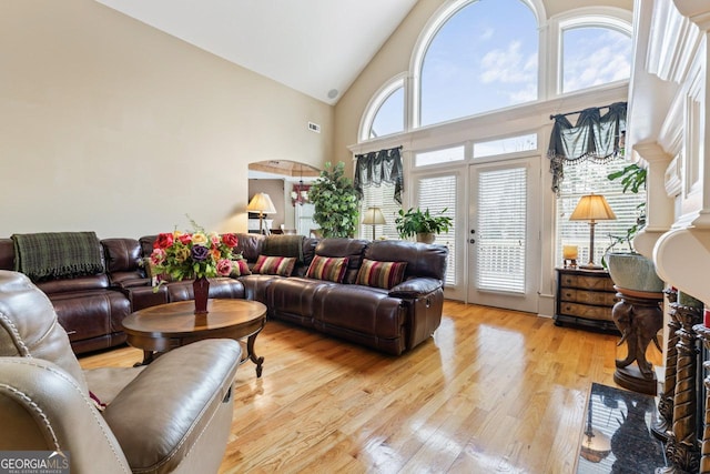 living room with french doors, high vaulted ceiling, and light hardwood / wood-style floors