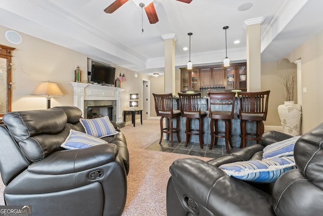 living room with dark colored carpet, crown molding, ornate columns, a tile fireplace, and ceiling fan