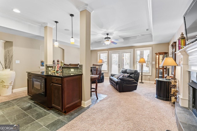 kitchen featuring hanging light fixtures, a tray ceiling, dark carpet, ceiling fan, and a premium fireplace