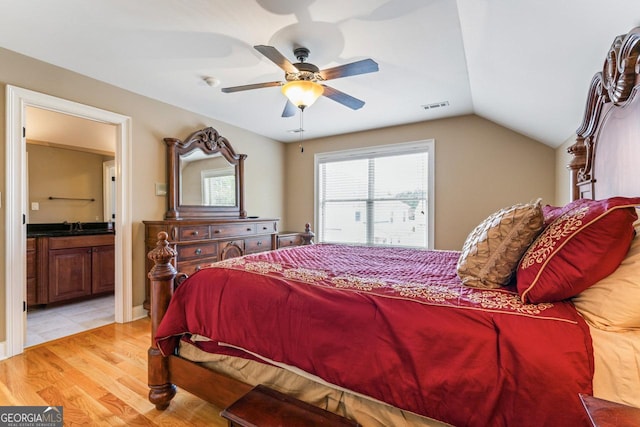 bedroom with sink, ensuite bath, vaulted ceiling, light wood-type flooring, and ceiling fan