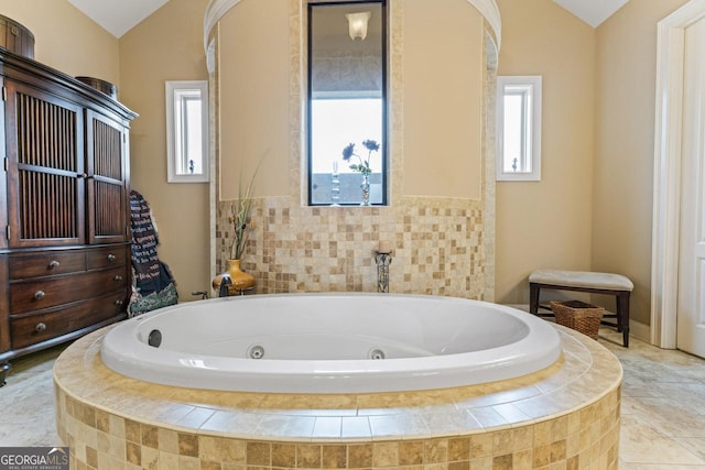 bathroom with a healthy amount of sunlight, vaulted ceiling, and tiled tub