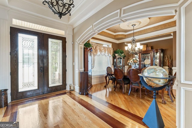 foyer featuring crown molding, wood-type flooring, french doors, and a chandelier