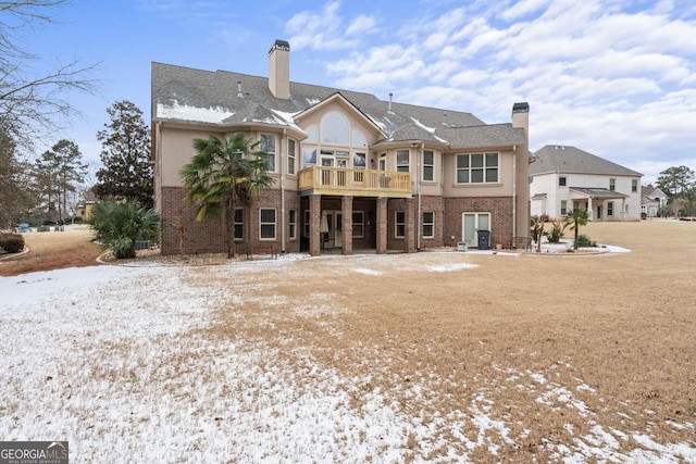 snow covered house featuring a balcony