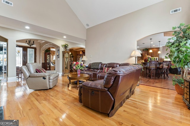 living room featuring high vaulted ceiling, light hardwood / wood-style floors, and french doors