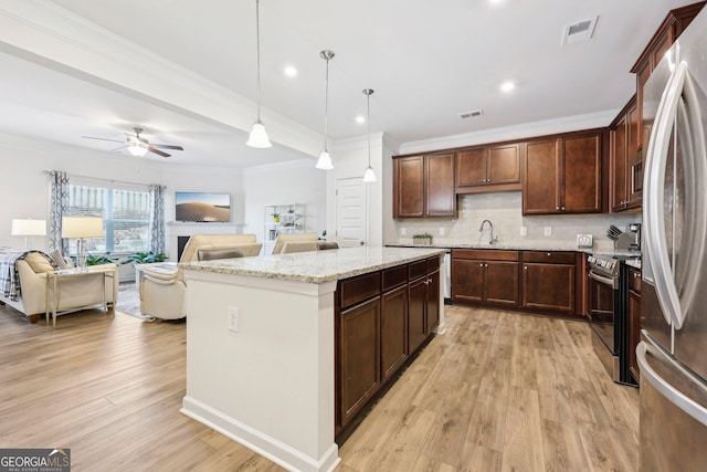 kitchen featuring sink, appliances with stainless steel finishes, pendant lighting, light stone countertops, and decorative backsplash