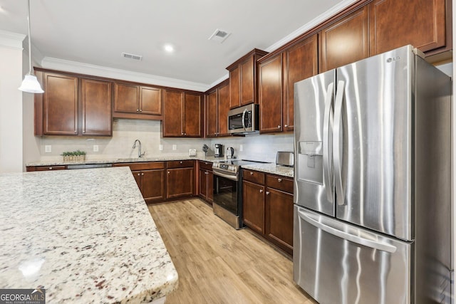 kitchen with appliances with stainless steel finishes, pendant lighting, sink, crown molding, and light stone countertops