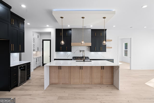 kitchen featuring decorative light fixtures, beverage cooler, decorative backsplash, a large island, and light stone counters