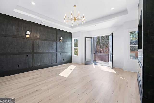 interior space featuring an inviting chandelier, a tray ceiling, and light hardwood / wood-style flooring