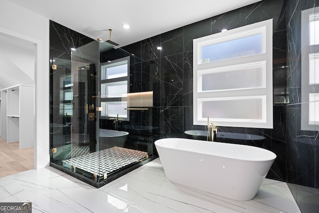 bathroom with shower with separate bathtub, a wealth of natural light, and tile walls