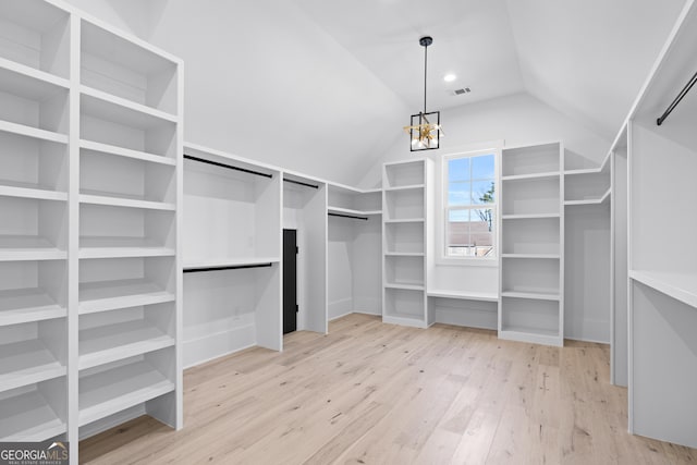 walk in closet featuring lofted ceiling, a notable chandelier, and light hardwood / wood-style floors