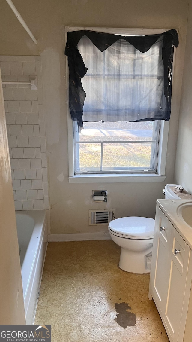 bathroom with plenty of natural light, vanity, toilet, and a tub