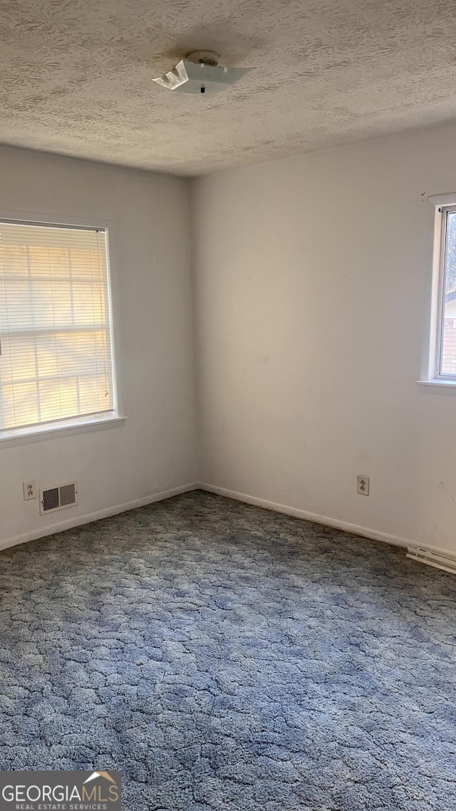 carpeted spare room featuring a textured ceiling