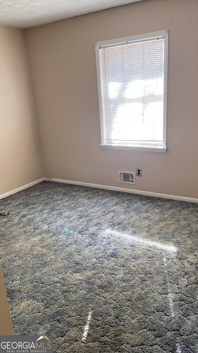 carpeted spare room featuring a textured ceiling