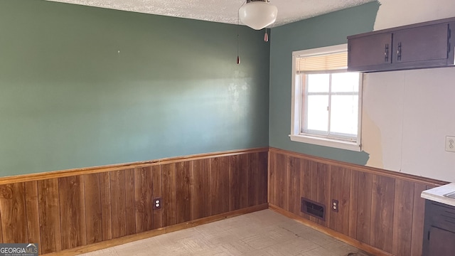 unfurnished room with wooden walls and a textured ceiling