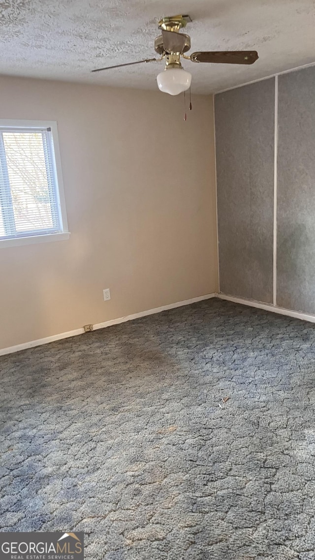 carpeted empty room with ceiling fan and a textured ceiling