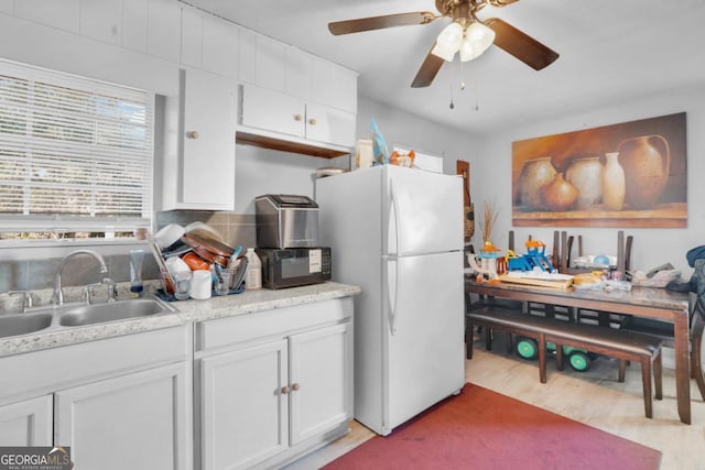 kitchen with sink, white cabinetry, white refrigerator, decorative backsplash, and light wood-type flooring