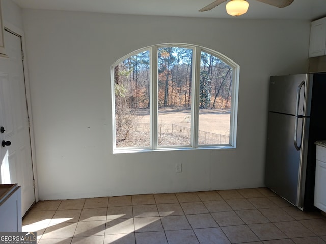 unfurnished dining area with a healthy amount of sunlight, light tile patterned floors, and ceiling fan