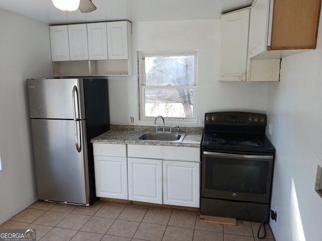 kitchen featuring stainless steel refrigerator, sink, white cabinets, light tile patterned floors, and electric stove