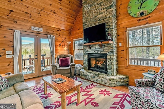 living room with french doors, light hardwood / wood-style floors, and wood walls