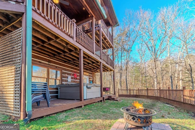 rear view of property featuring a yard, a jacuzzi, ceiling fan, and a fire pit