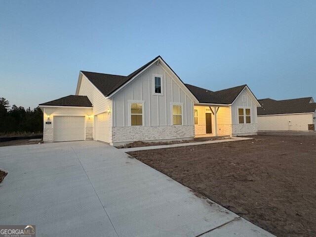 modern farmhouse with driveway, a garage, and board and batten siding