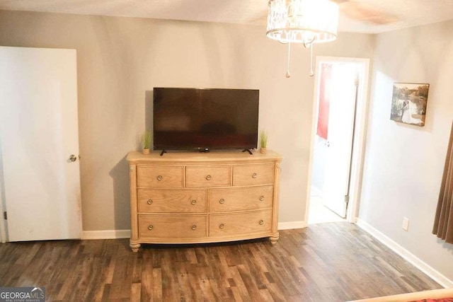 unfurnished bedroom featuring an inviting chandelier and dark hardwood / wood-style floors