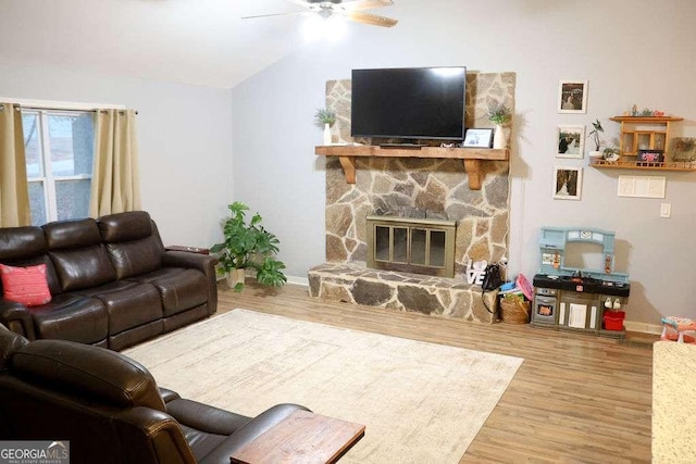 living room with ceiling fan, wood-type flooring, a fireplace, and lofted ceiling