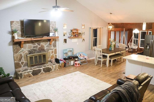 living room featuring ceiling fan, wood-type flooring, a fireplace, and high vaulted ceiling