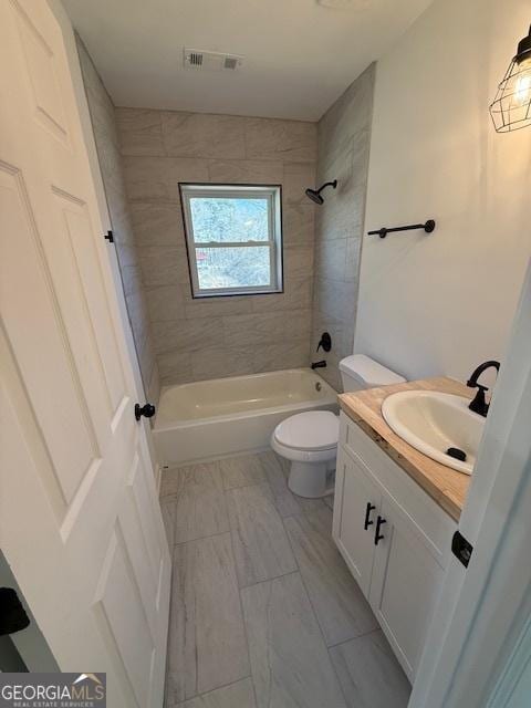 full bathroom featuring vanity, tiled shower / bath, and toilet