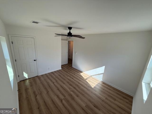 empty room featuring dark wood-type flooring and ceiling fan