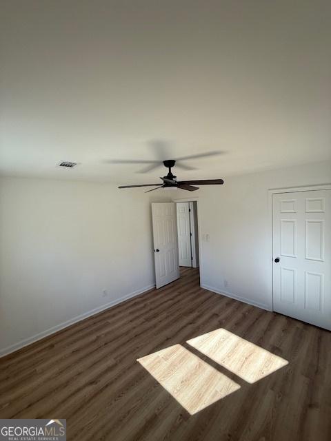 unfurnished bedroom featuring dark wood-type flooring and ceiling fan