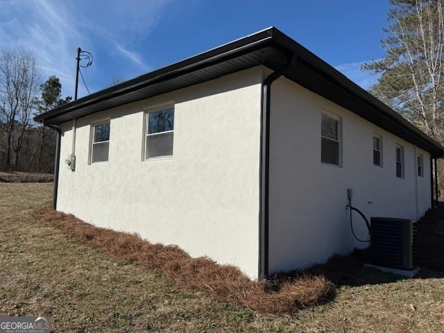 view of property exterior with a lawn and central air condition unit